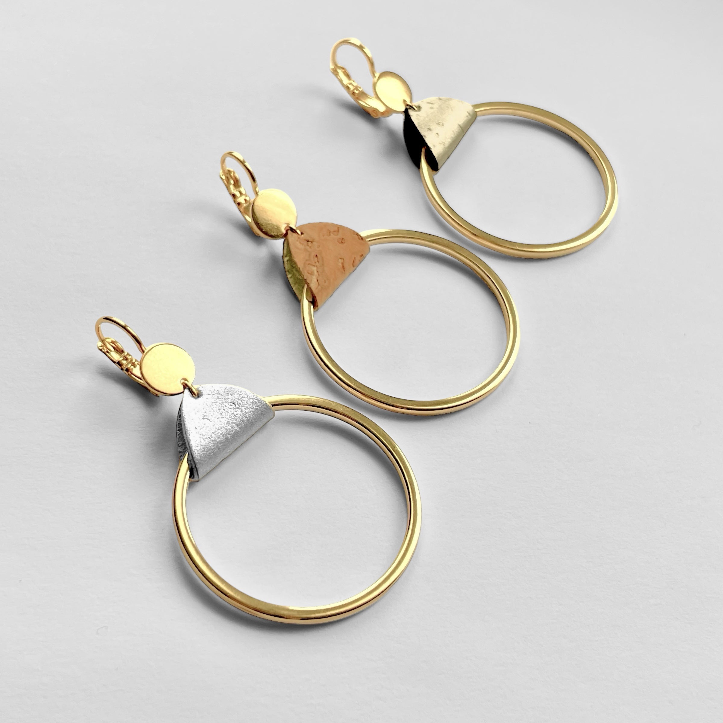 3 boucles d'oreilles dorées avec grands anneaux créoles avec de fines pièces de liège brut, doré et argenté, sur fond gris