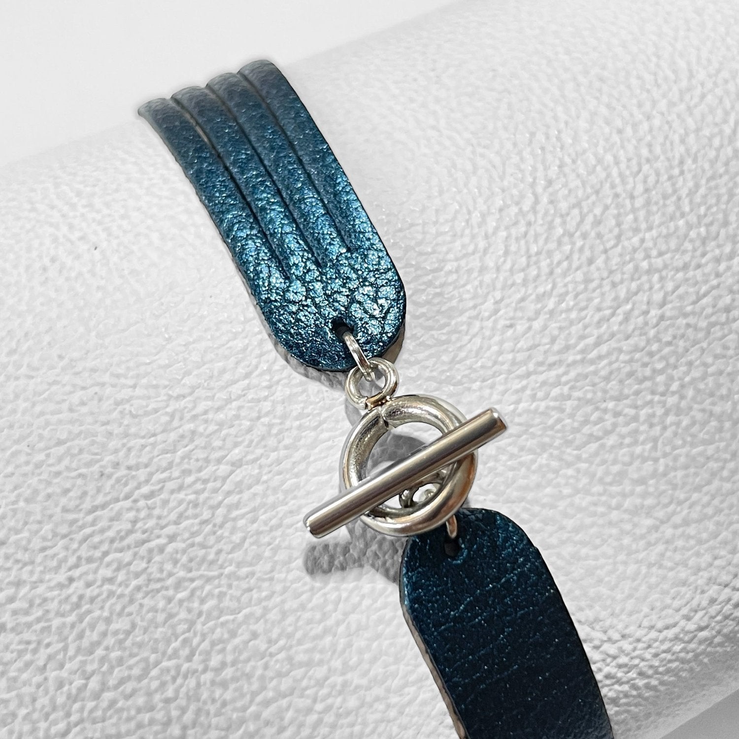 Bracelet en cuir doré bleu nuit métallisé à 4 liens avec petite boucle argentée, vu de dessous, sur fond blanc