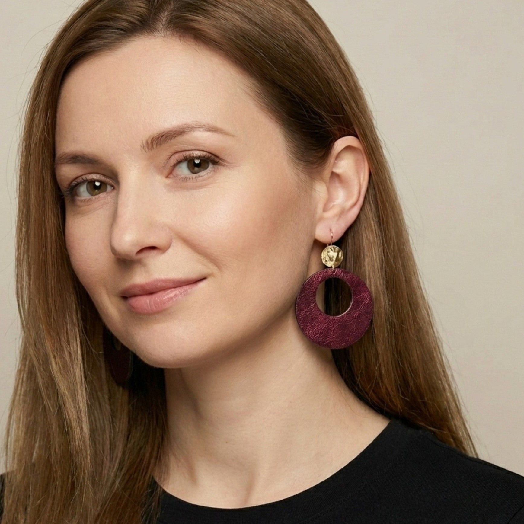 Nune grande boucle d'oreilles créole Zoa au style vintage en cuir grenat métallisé, montée sur dormeuse martelée dorée à l'or fin, portée à l'oreille