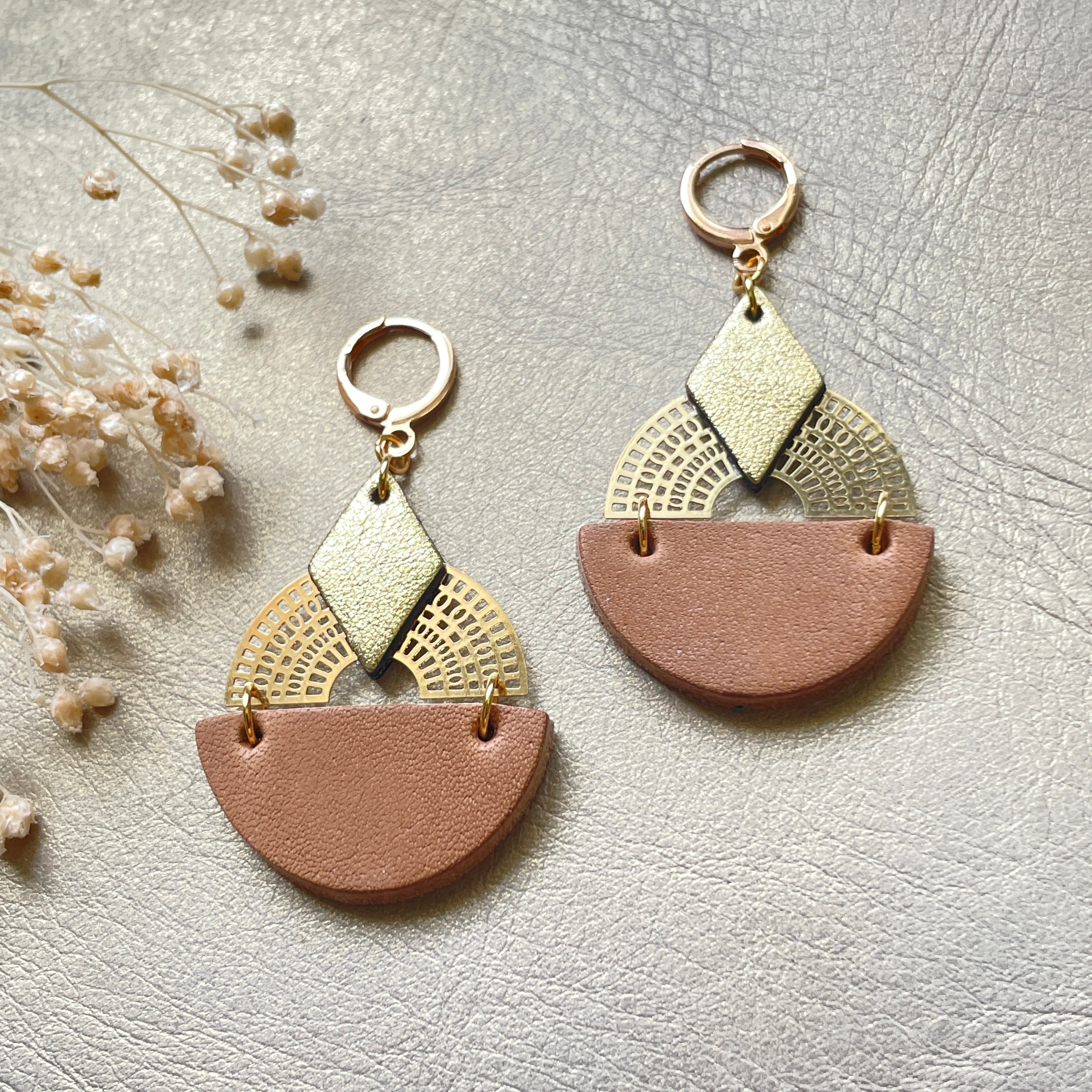 Boucles d'oreilles dorées Nune modèle Echo en cuirs beige amande et doré satiné sur fond gris doré, vues de face