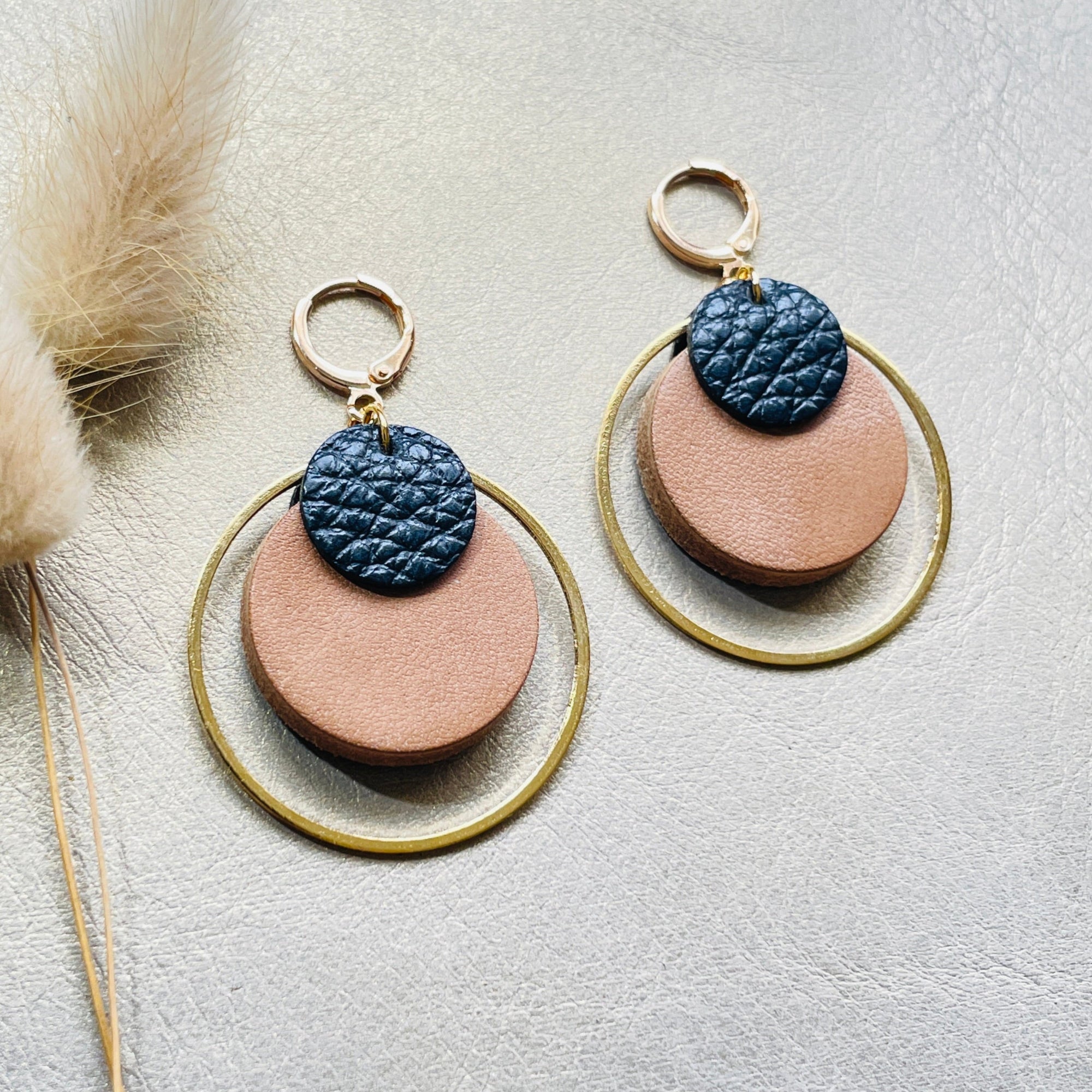 boucles d'oreilles dorées Nune modèle Danaé en cuirs beige amande et noir grainé sur fond gris doré