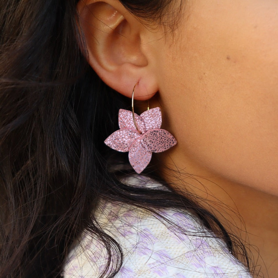 Nune petite créole Jasmin en cuir rose brillant et anneaux dorés, portée à l'oreille