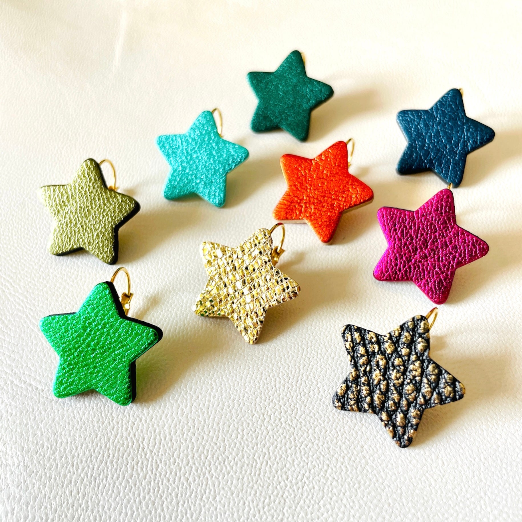 NUNE Boucles d'oreilles Diva en forme d'étoiles en cuir recyclé doré façon serpent, noir grainé or, vert métallisé, kaki métallisé, vert sapin métallisé, orange sanguine métallisé, bleu nuit métallisé, turquoise métallisé et fushia métallisé, sur fond blanc