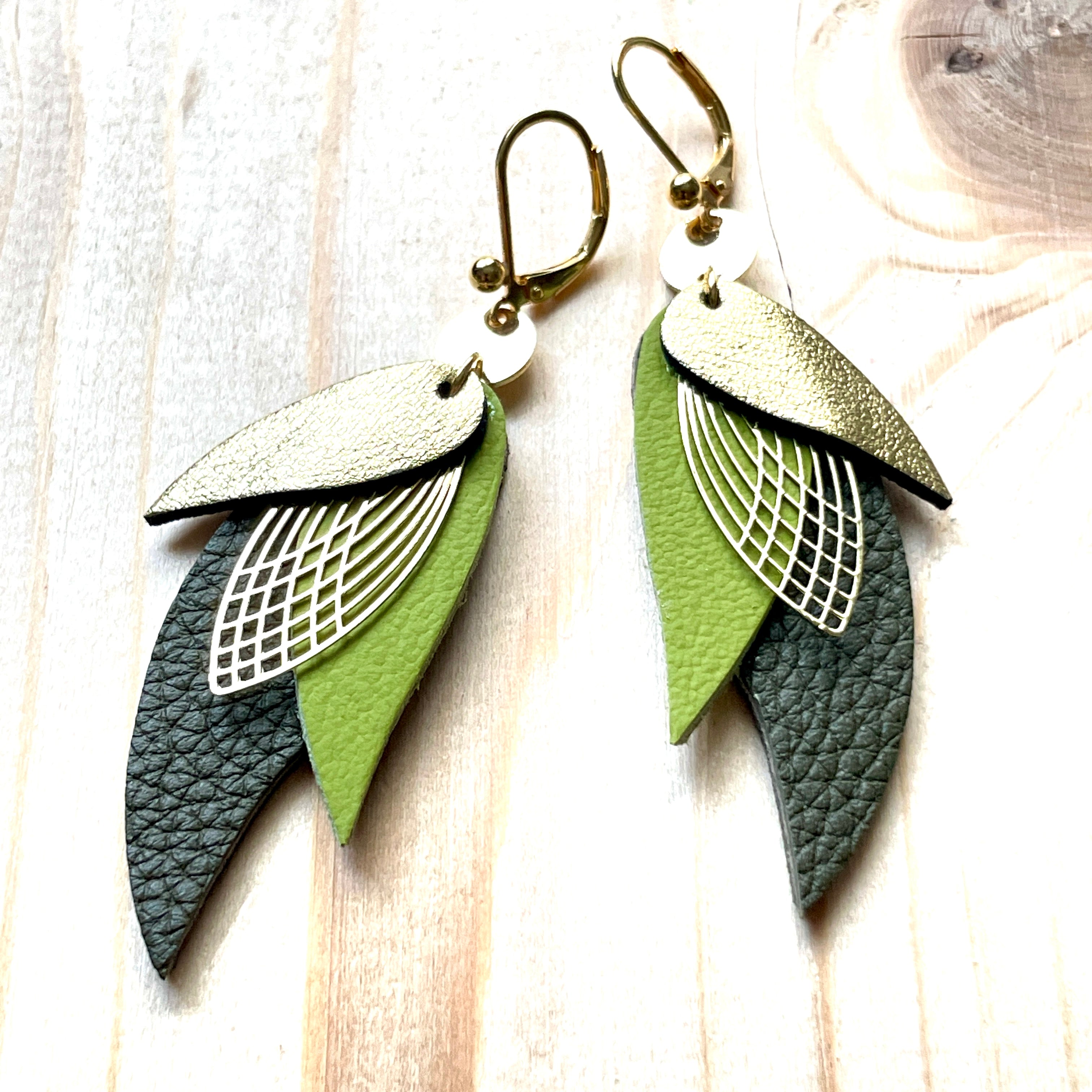 boucles d'oreilles dorées Nune modèle Ara en plumes de cuirs doré satiné, vert olive et kaki grainé sur bois clair
