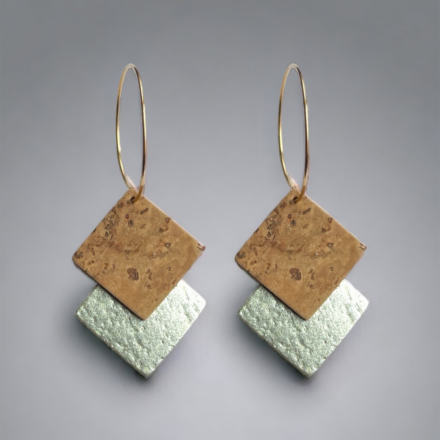Boucles d'oreilles créoles dorées en liège doré antique et argenté. Forme géométrique double-losanges imbriqués, sur fond gris