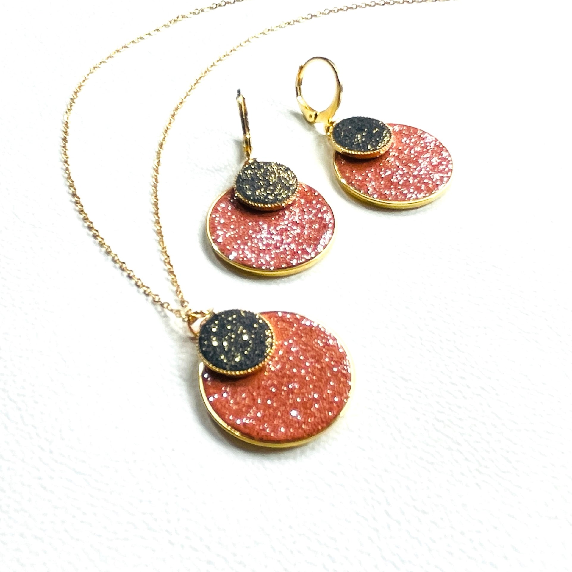 Parure Collier et boucles d'oreilles Bulles pailletées Nune, court doré avec pendentif rond composé de doubles sertis de cuirs pailletés brique et noir, sur fond blanc