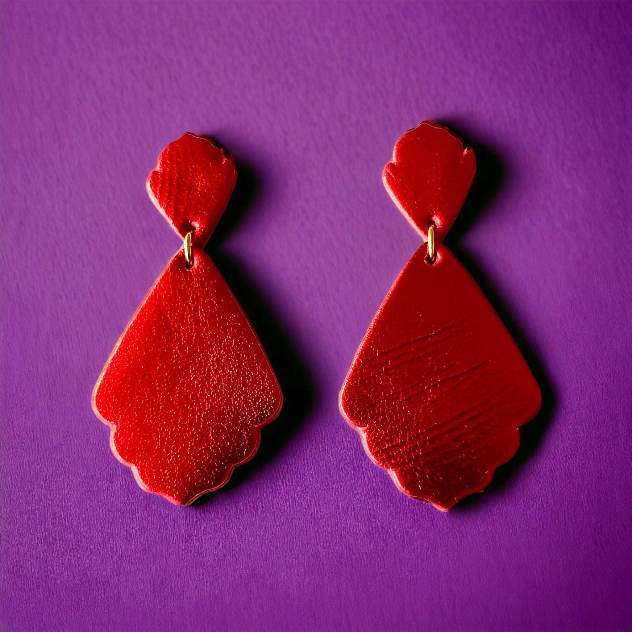 paire de boucles d'oreilles rouge métallisé de style rétro baroque, sur fond violet