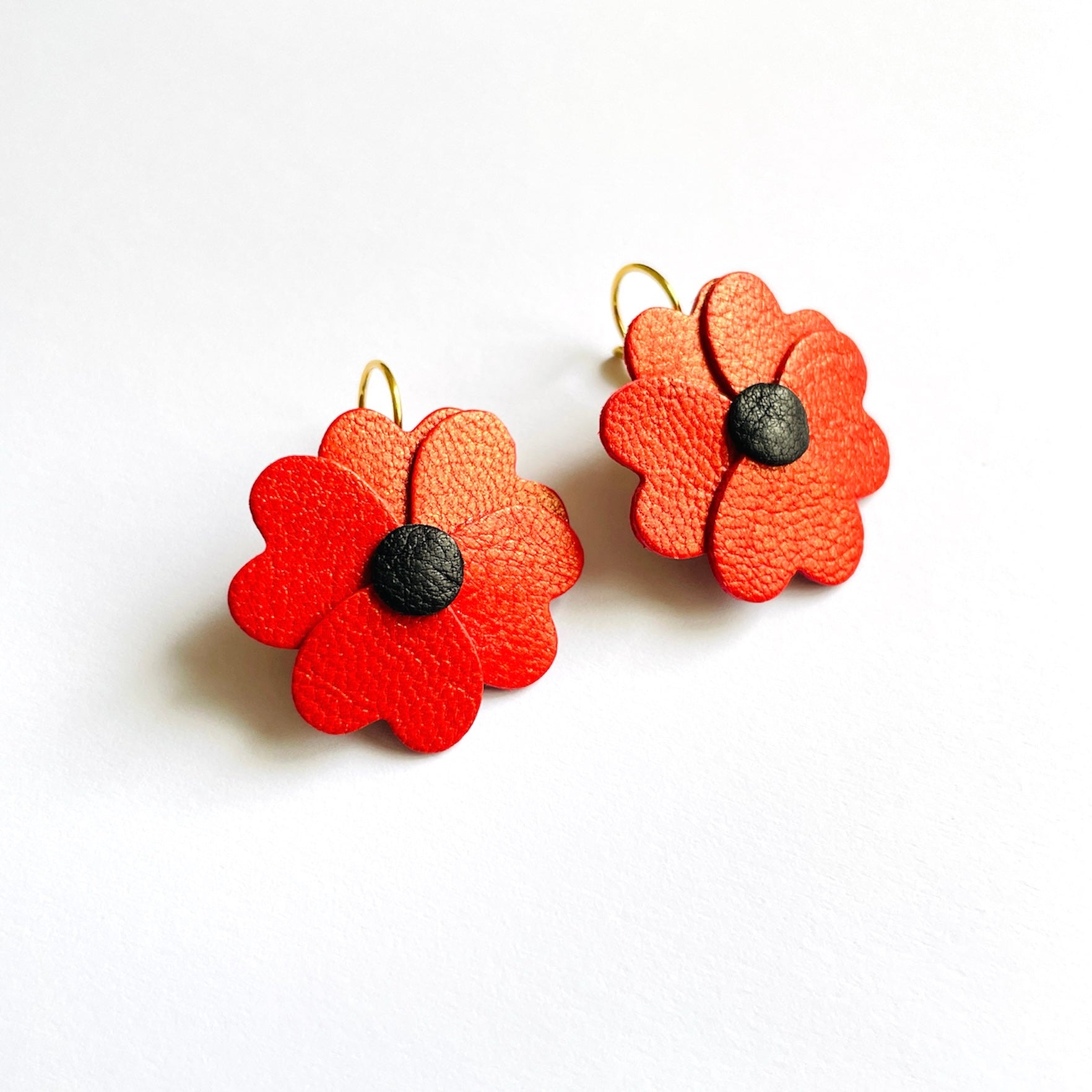 Boucles d'oreilles Nune en forme de petites fleurs , modèle Lalie, en cuirs coquelicot nacré & noir sur fond blanc