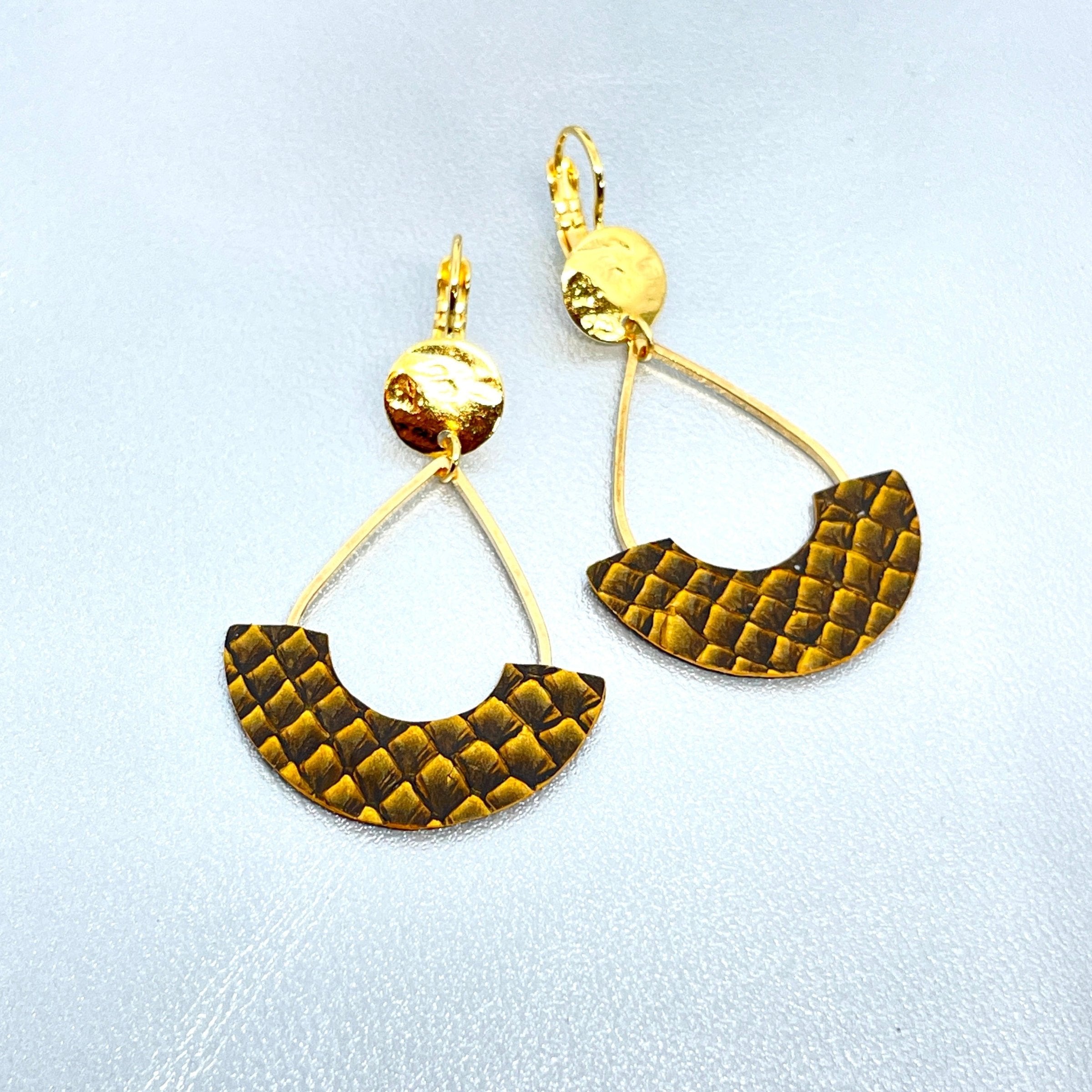 Boucles d'oreilles Anoush de Nune, dorées à l'or fin avec cuir marin, cuir de poisson saumon ocre écaille, en forme de demi-lune, sur fond cuir gris argenté