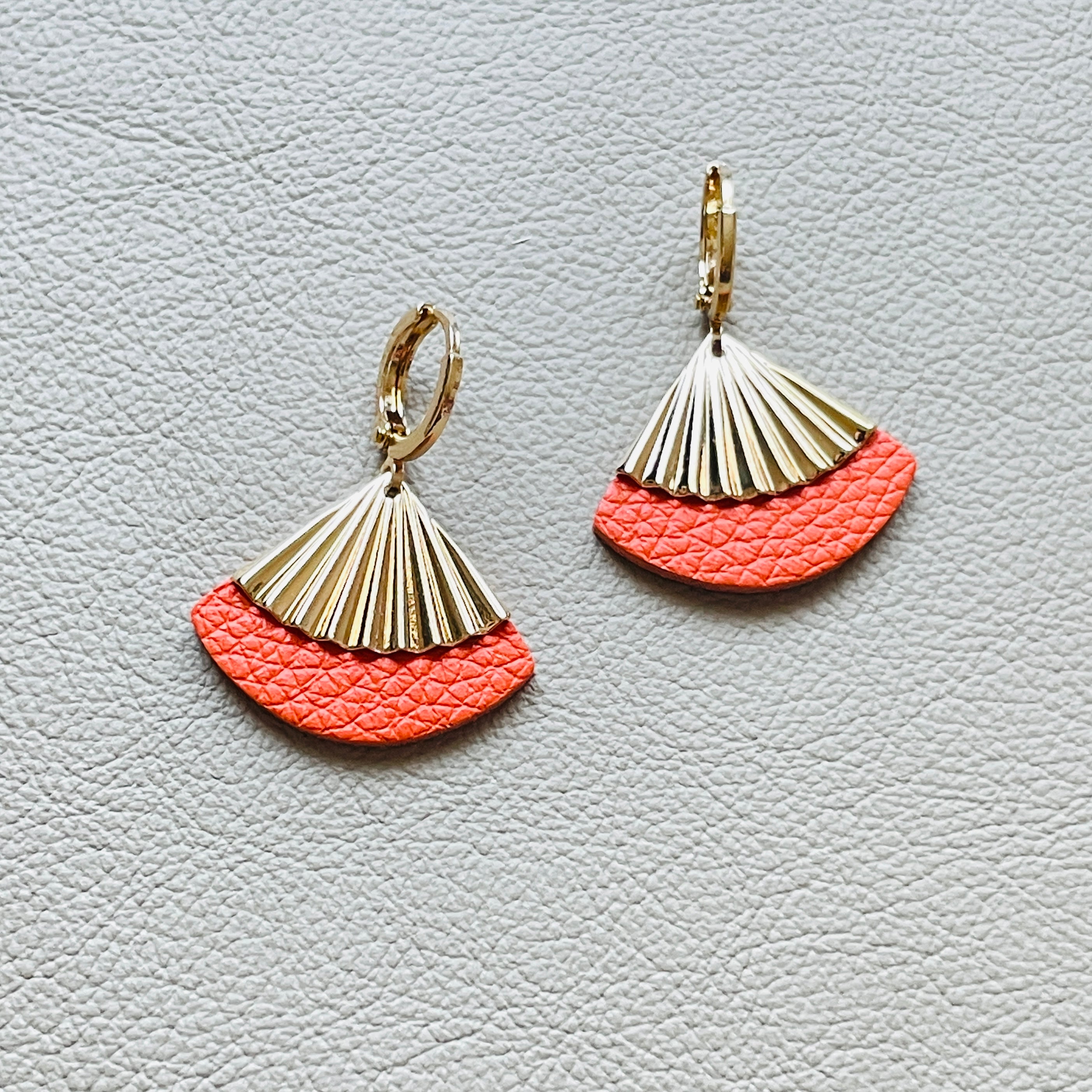 Boucles d'oreilles dorées Nune modèle Alya avec sequin éventail et pièces de cuir carotte grainé, sur fond cuir beige