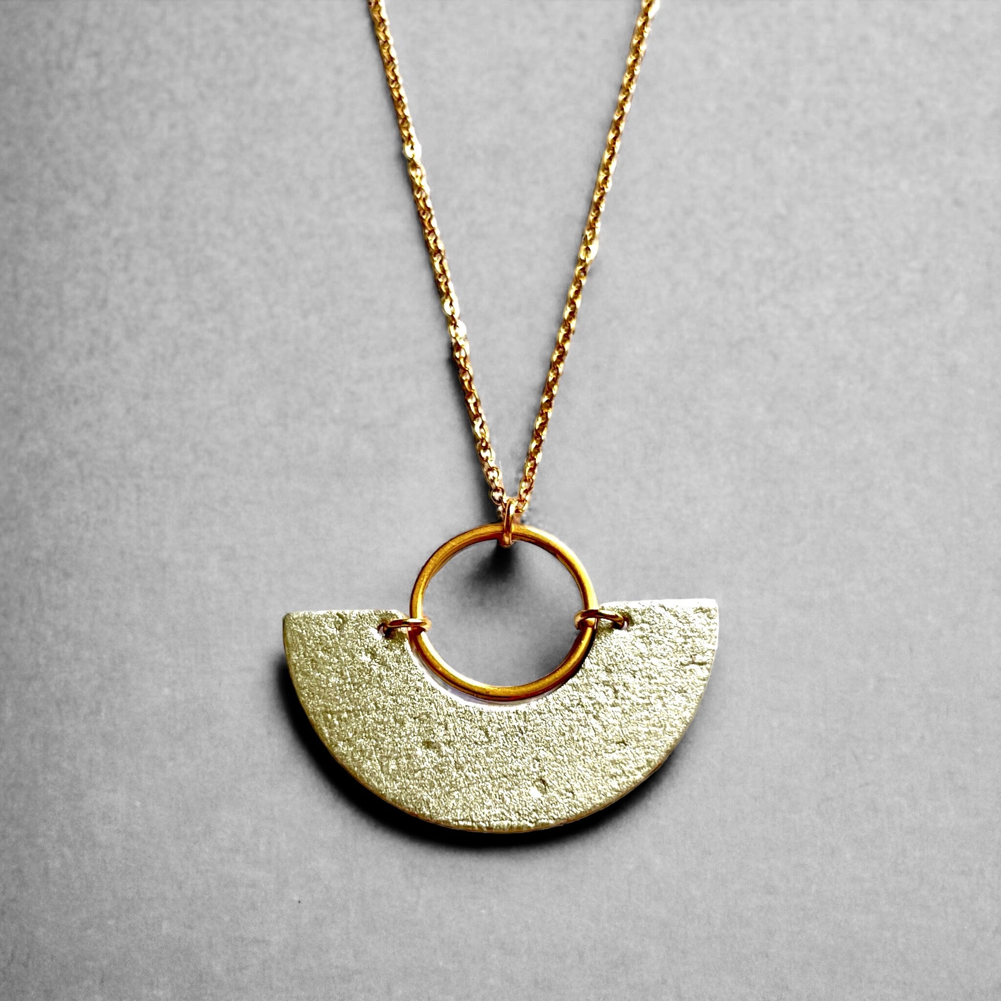 Collier fin doré avec pendentif en forme de demi-lune en liège doré antique, sur fond gris