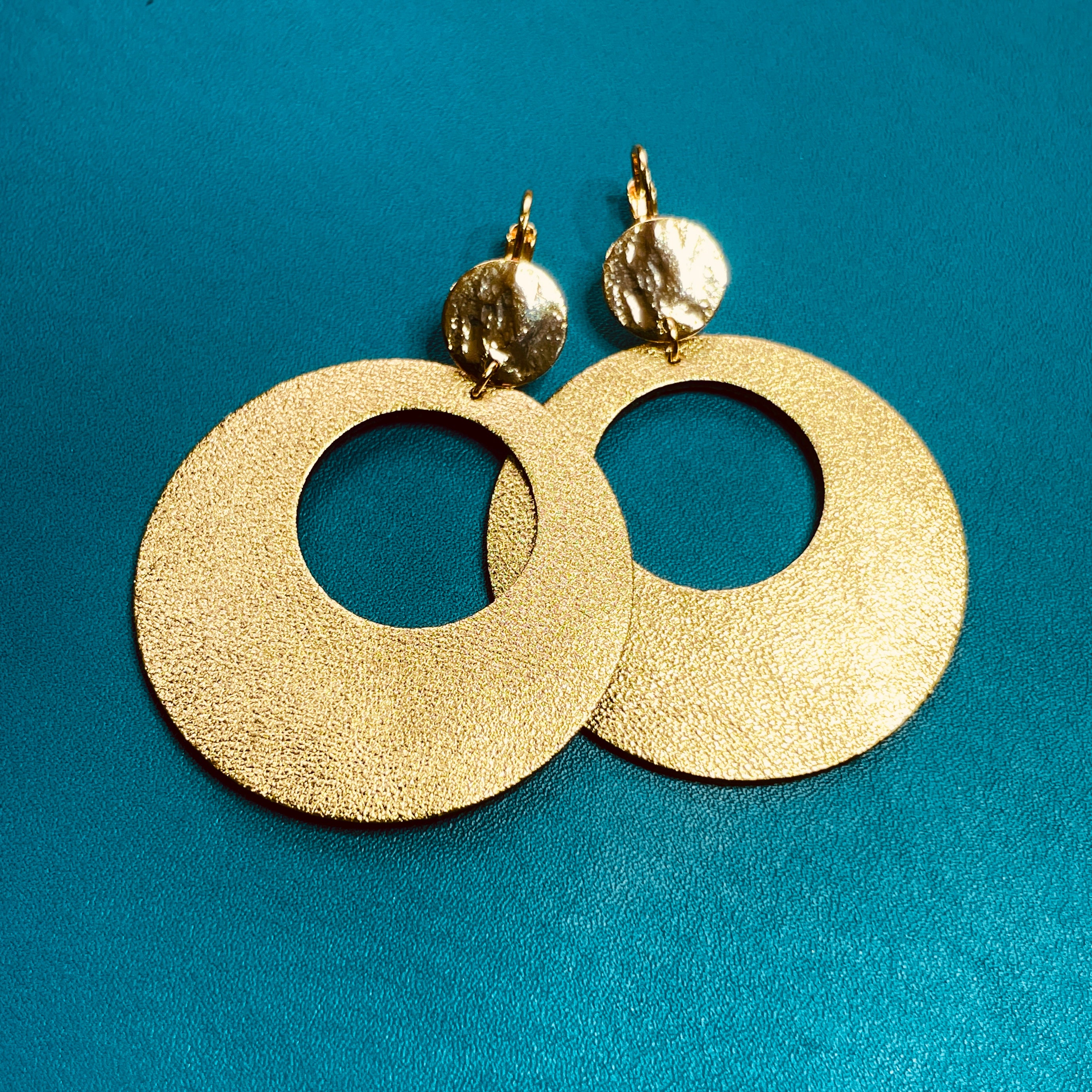 Nune grandes boucles d'oreilles créoles Zoa au style vintage en cuir doré satiné, et dormeuses martelées dorées à l'or fin, sur fond cuir vert canard