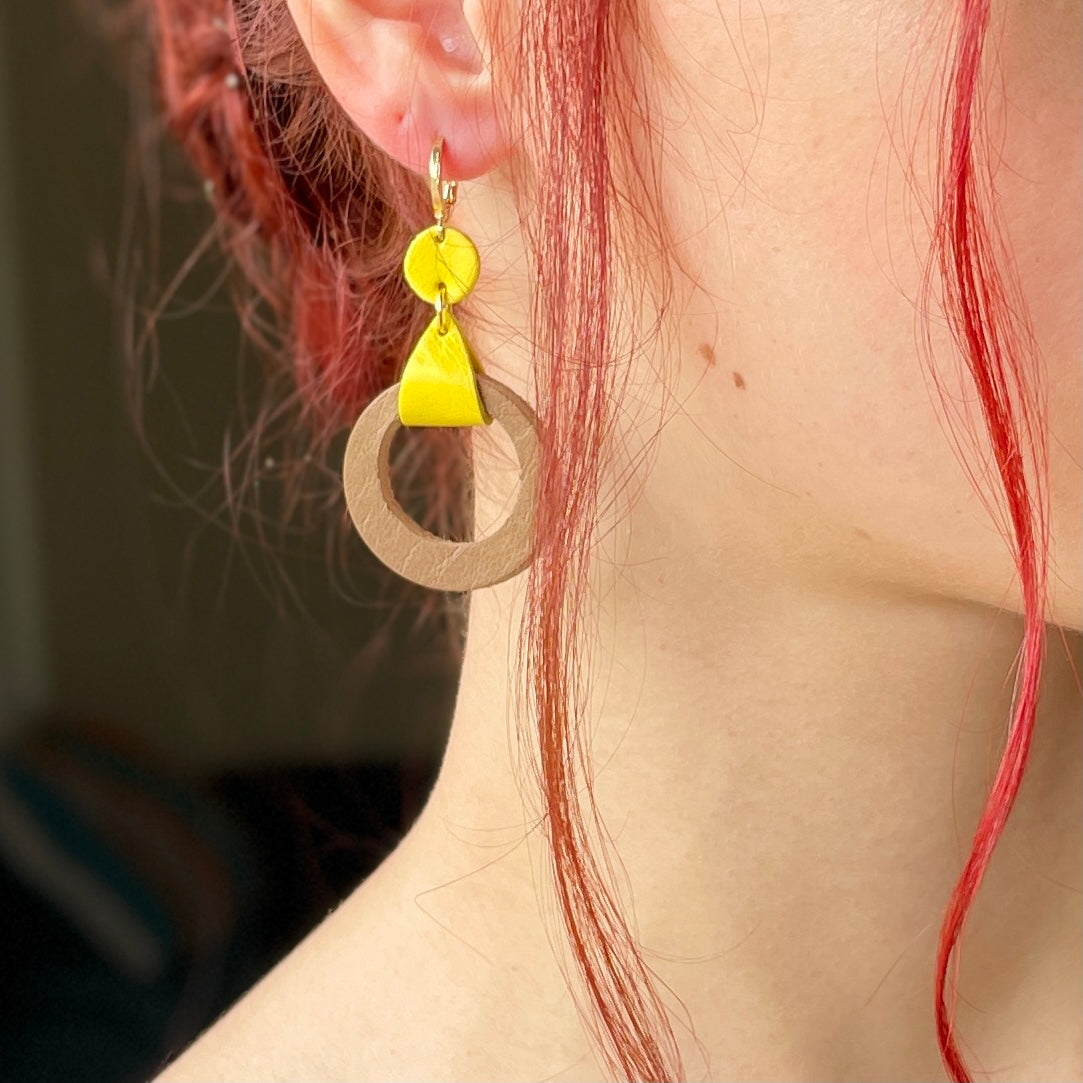 boucle d'oreille dorée Nune modèle Cyllène en cuirs beige amande et jaune citron portée par un modèle aux cheveux rouges et au teint pâle