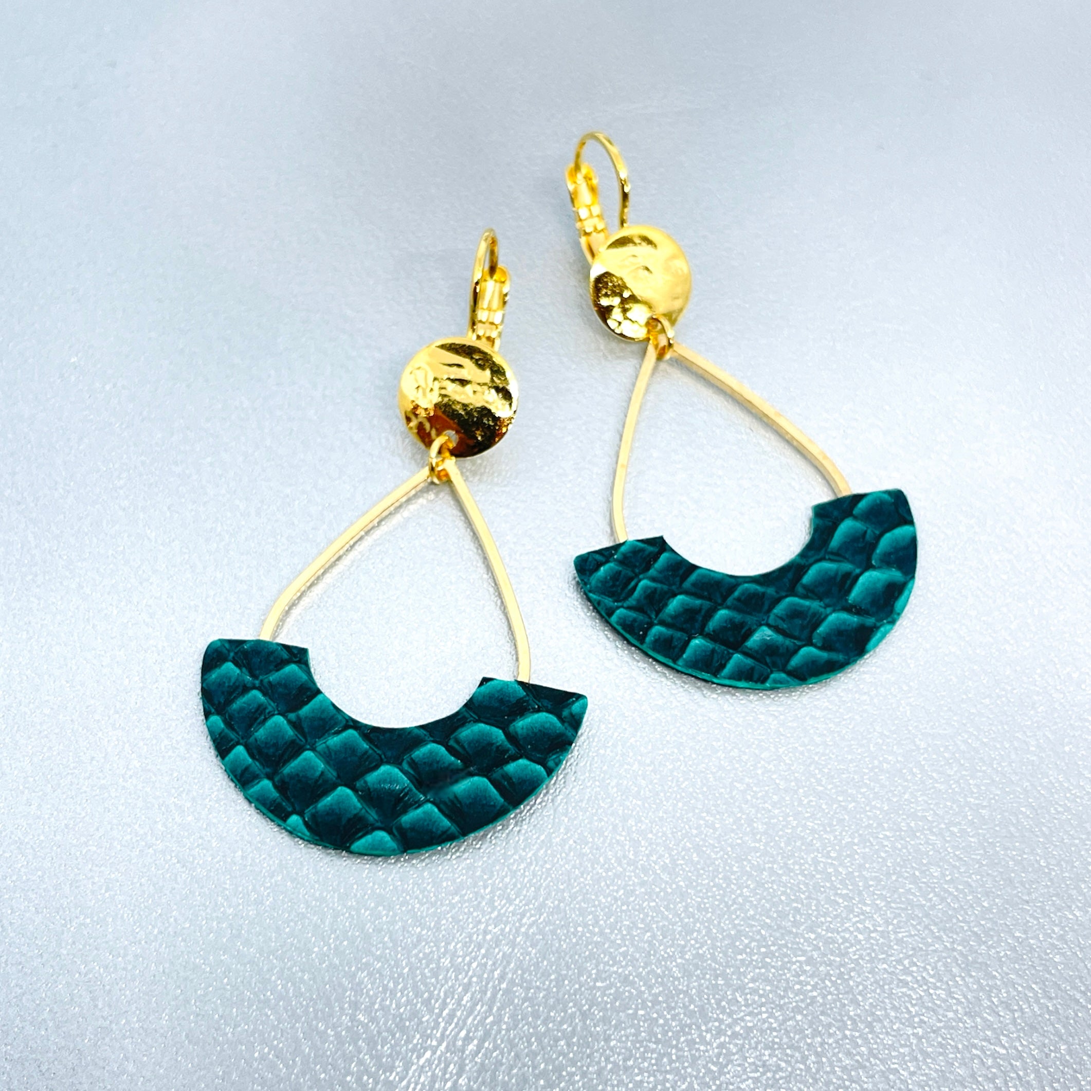 Boucles d'oreilles Anoush de Nune, dorées à l'or fin avec cuir marin, cuir de poisson saumon vert émeraude écaille, en forme de demi-lune, sur fond cuir gris argenté