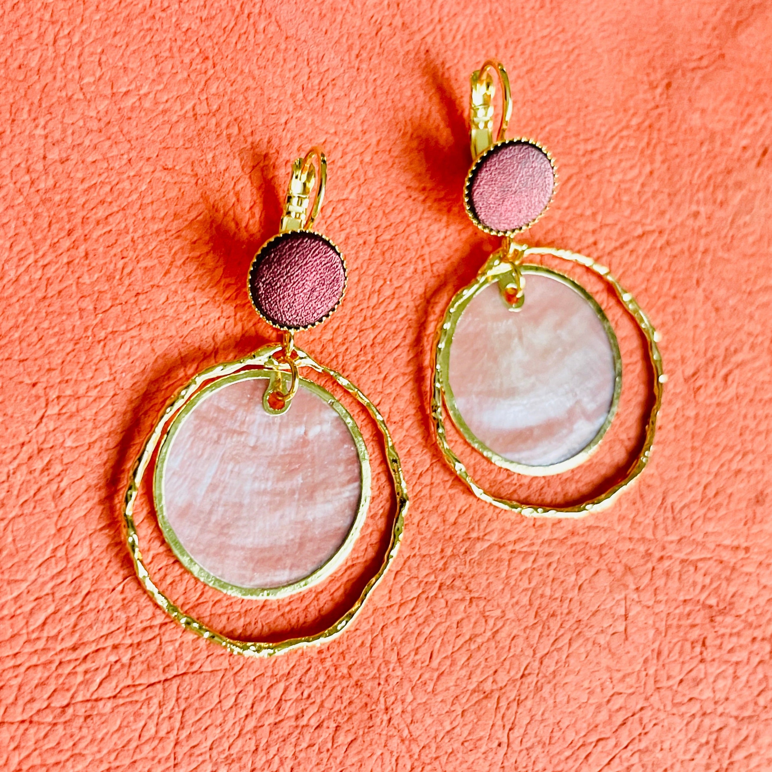 boucles d'oreilles dorées Nune modèle Bali Créoles Capiz en cuir grenat métallisé sur fond de cuir pêche
