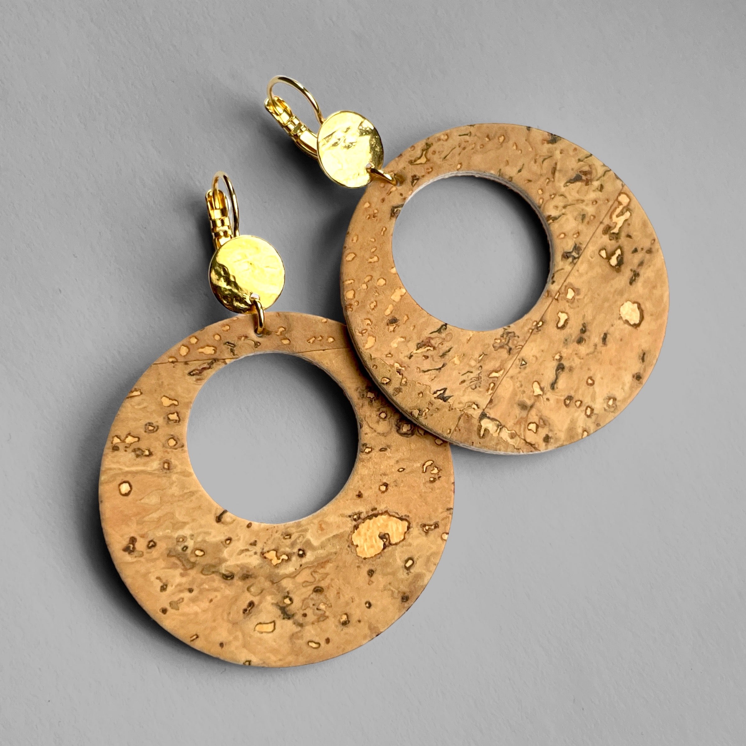 grandes boucles d'oreilles créoles Zoa au style vintage en liège brut, et dormeuses martelées dorées à l'or fin, sur fond gris