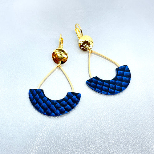 Boucles d'oreilles Anoush de Nune, dorées à l'or fin avec cuir marin, cuir de poisson saumon bleu saphir écaille, en forme de demi-lune, sur fond cuir gris argenté