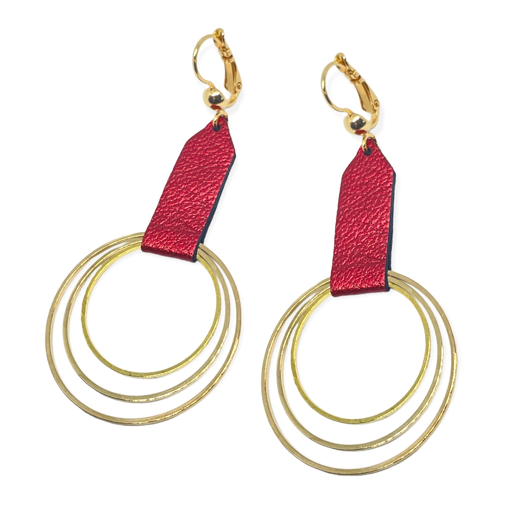 Grandes boucles d'oreilles dorées avec pendentifs en anneaux concentriques attachés par des rubans de cuir recyclé rubis métallisé, sur fond blanc. Modèle Dizzo