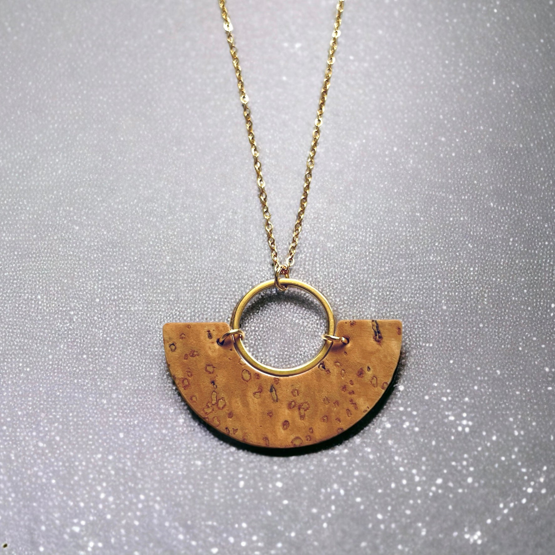 Collier fin doré avec pendentif en forme de demi-lune en liège brut, sur fond gris