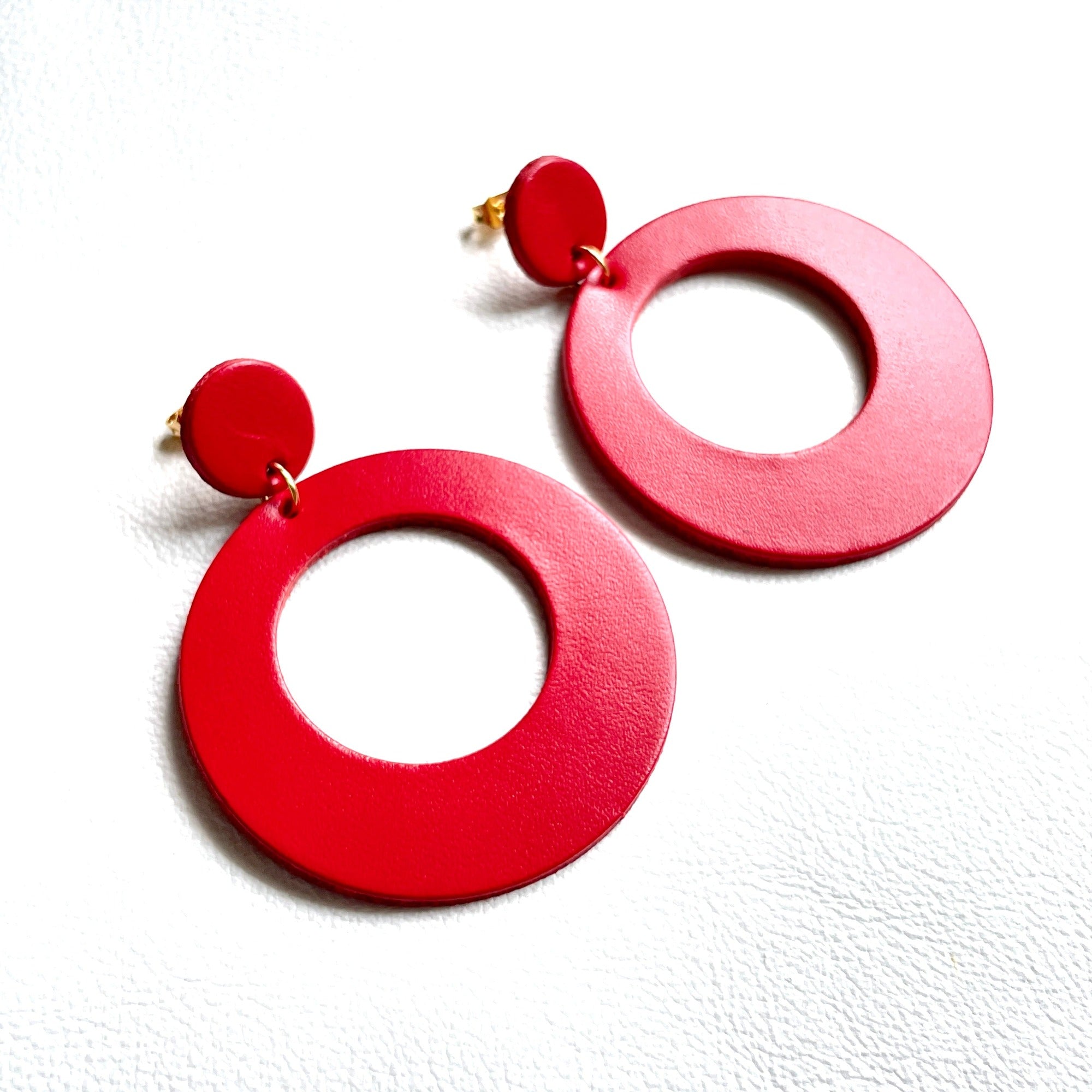 Boucles d'oreilles créoles tout cuir style vintage Nune modèle Lola en cuir upcyclé rouge, sur fond cuir blanc