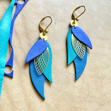 Charger l'image dans la galerie, boucles d'oreilles dorées Nune modèle Ara en plumes de cuir violet velours, bleu turquoise et bleu denim mat sur cuir beige