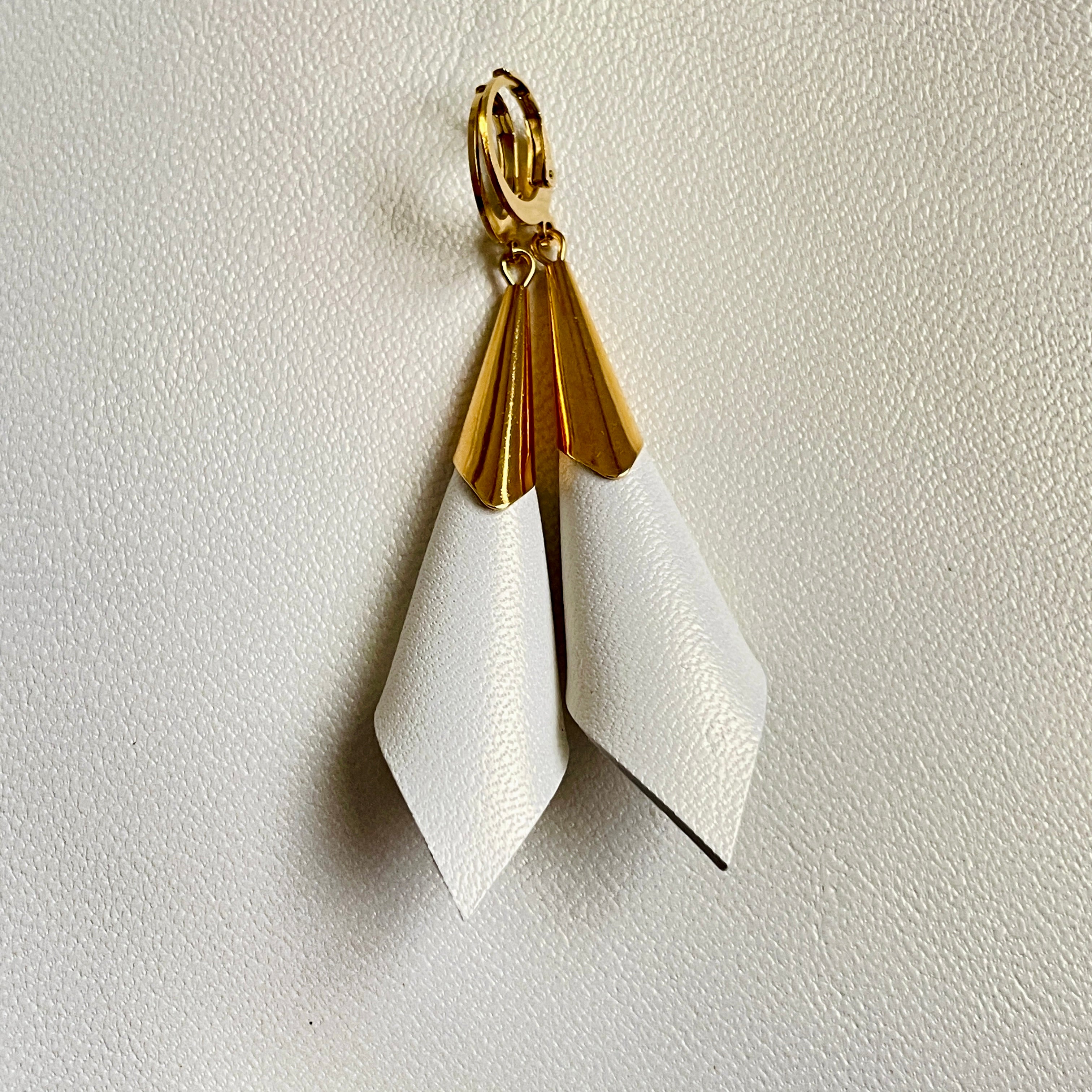 Boucles d'oreilles dorées Nune modèle Alice en forme de cônes de cuir blanc cassé nacré, sur fond cuir blanc cassé nacré
