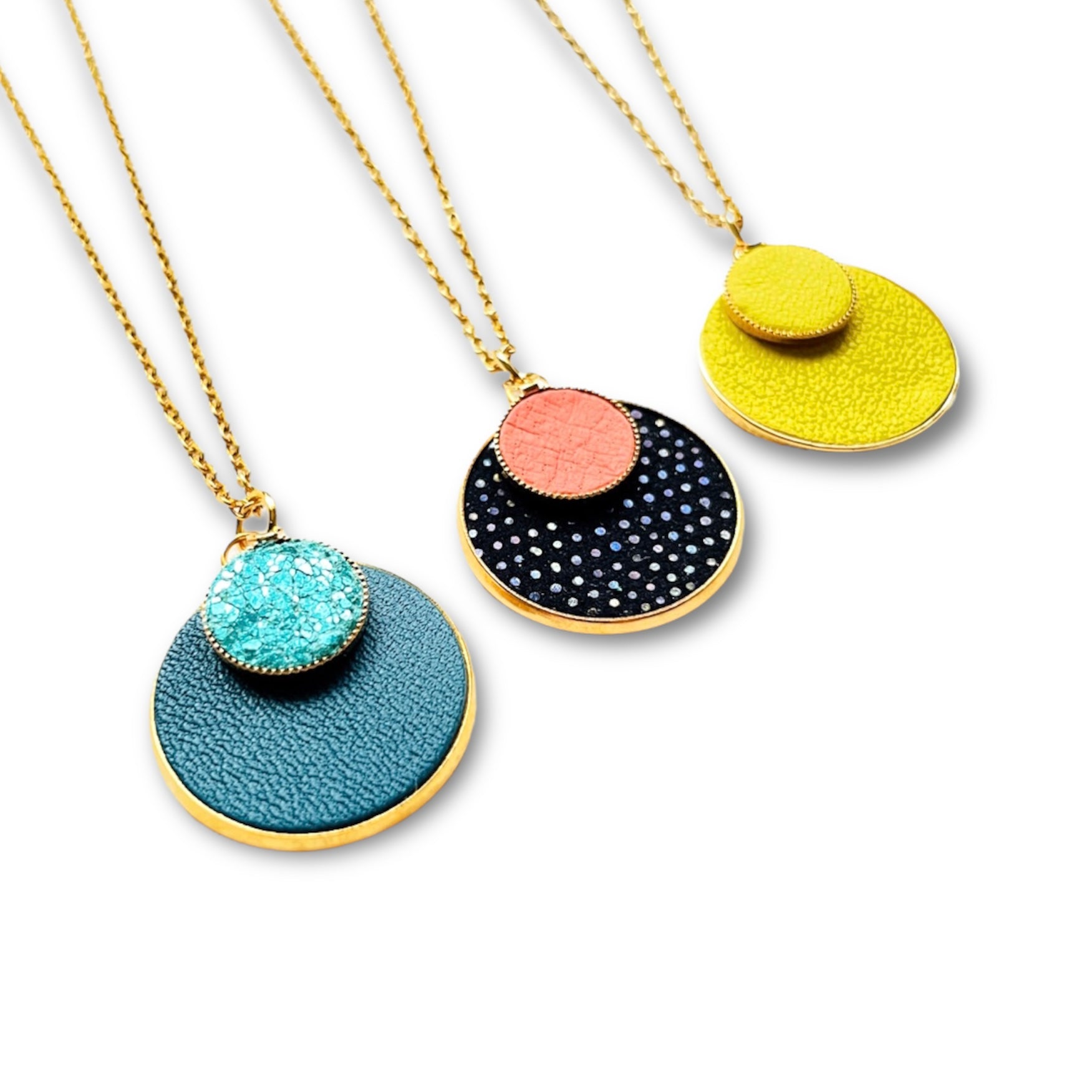 Trois Colliers Bulles Nune, court doré avec pendentif rond composé de doubles sertis de cuirs vert canard et vert émeraude brillant intense, noir grainé irisé et saumon clair, et jaune citron, sur fond blanc