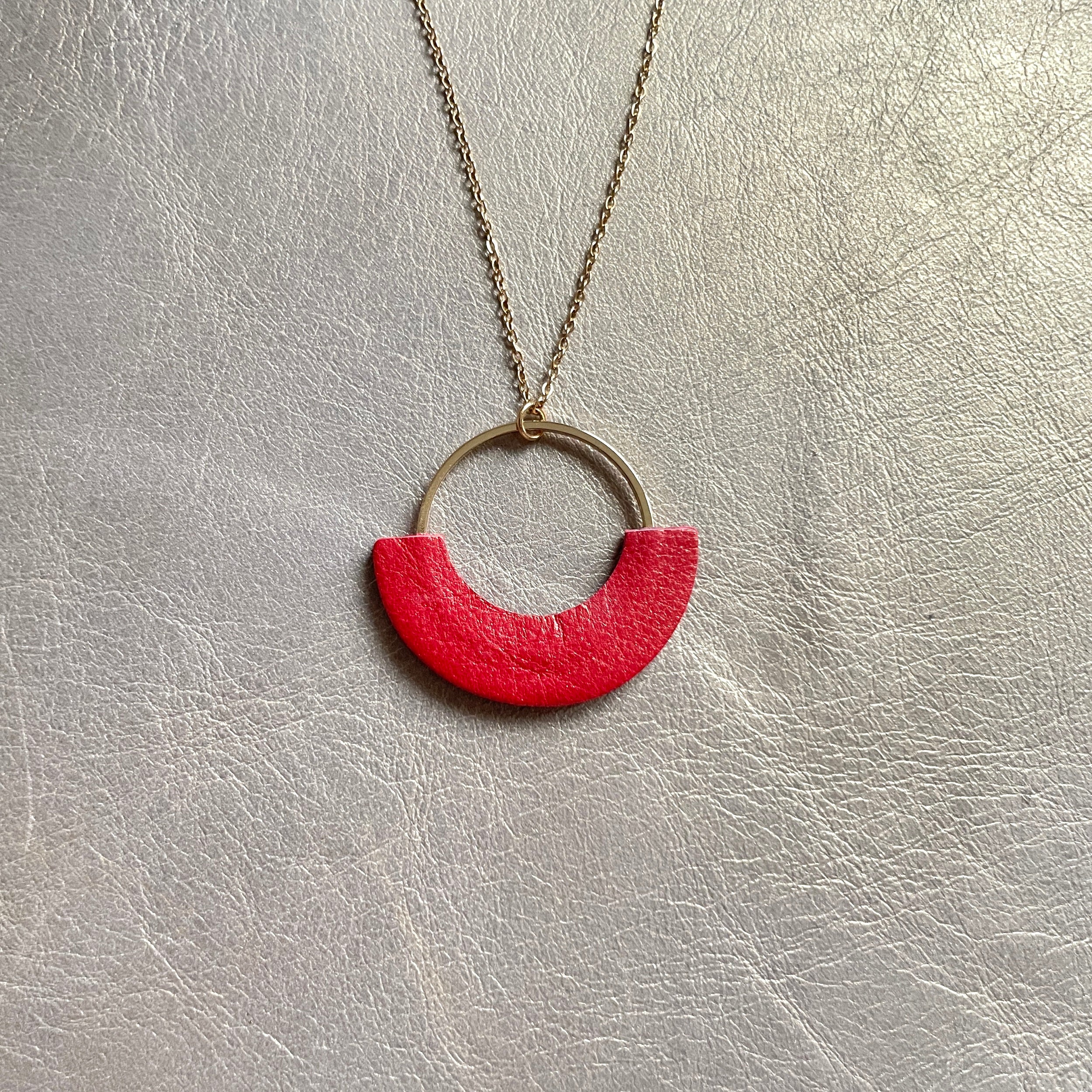 Collier fin Nune modèle Mezzaluna doré avec pendentif rond en forme de demi-lune en cuir recyclé coquelicot nacré, vue de face, sur fond beige doré