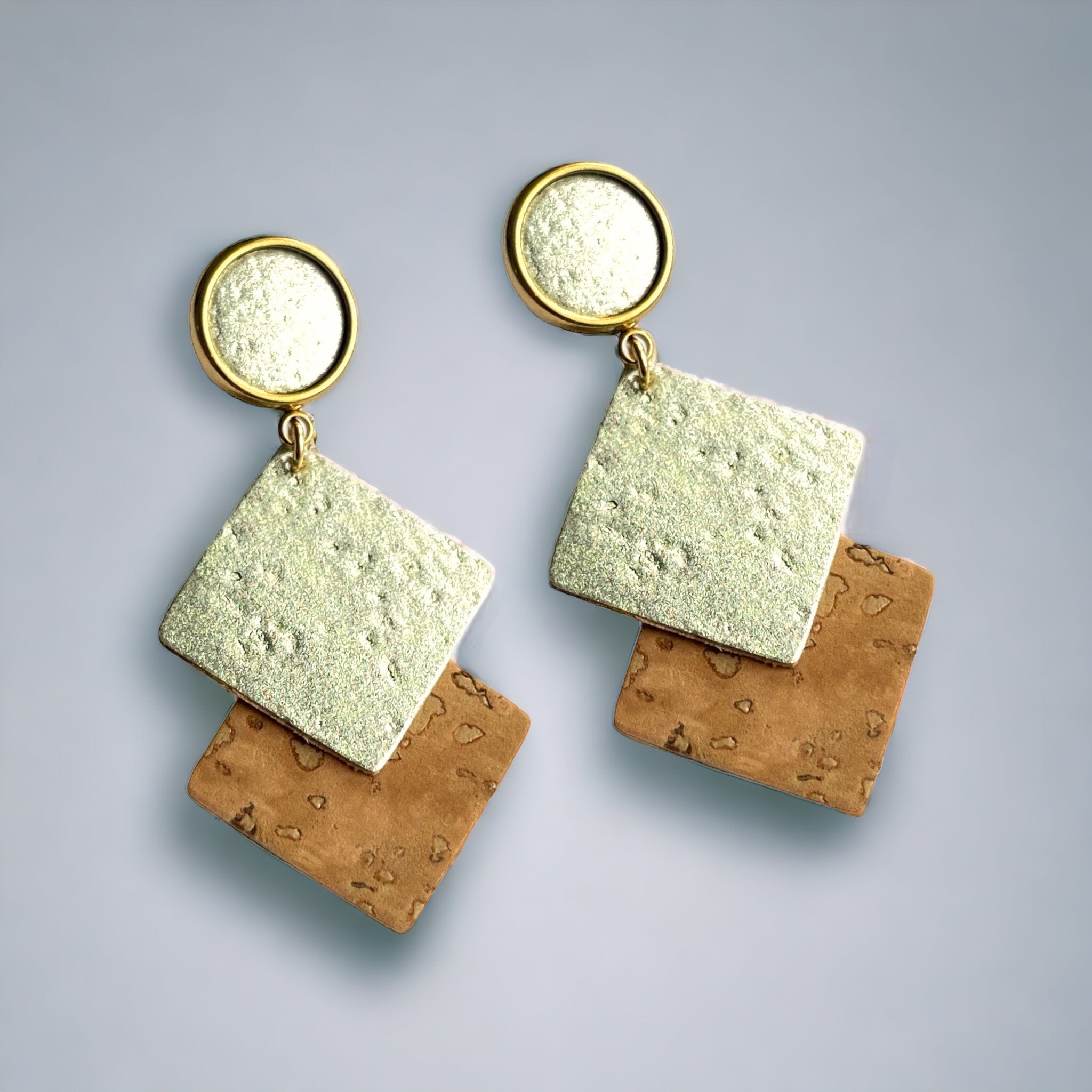 Boucles d'oreilles dorées avec puces cabochon et duo de losanges en liège brut et doré antique, sur fond gris