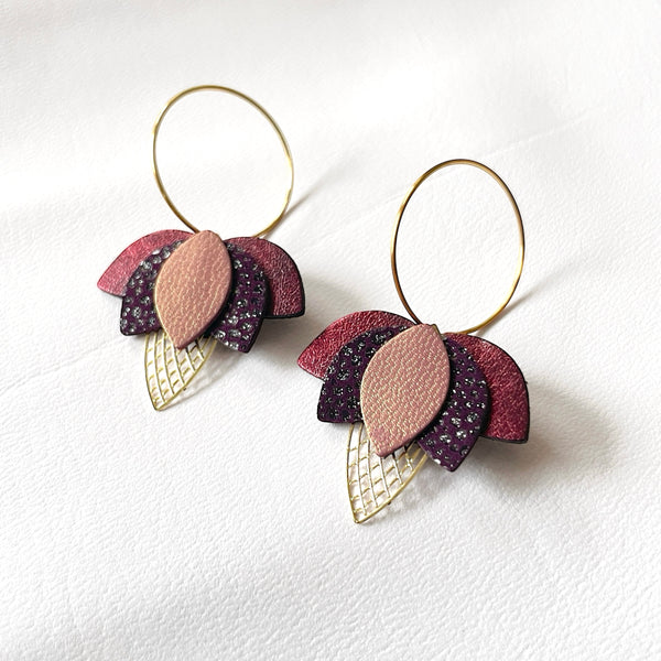 Créoles dorées en forme de fleurs de Lotus en cuirs grenat métallisé, prune irisé et vieux rose nacré sur fond blanc