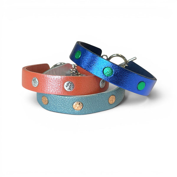 3 Bracelets argentés empilés en cuirs bicolore bleu  cobalt métallisé et vert métallisé, corail nacré et argent brillant froissé, et bleu gris nacré et or rosé froissé, empilés les uns sur les autres, sur fond blanc