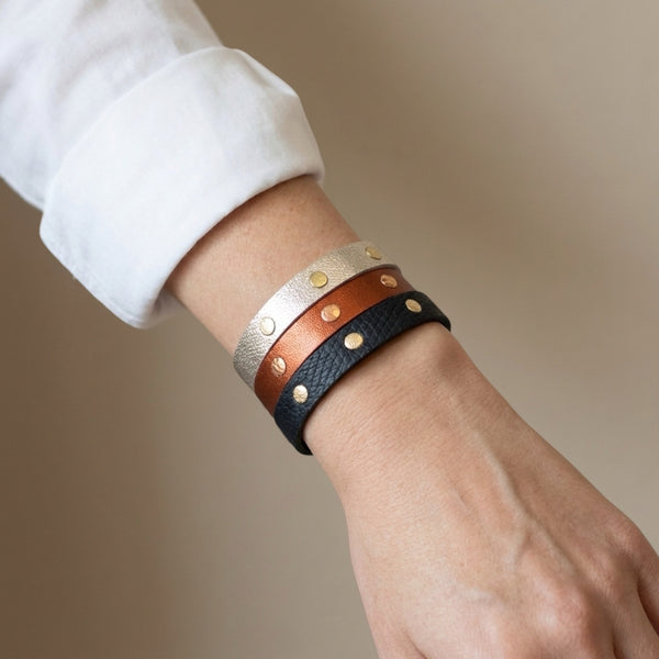 3 Bracelets dorés en cuirs bicolore argent et or, terracotta métallisé et or rosé froissé, et noir grainé et or, portés au poignet en mode stacking