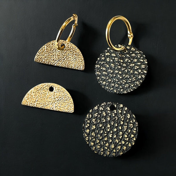 Boucles créoles dorées avec pendentifs en forme de disques et demi-lunes en cuirs noirs grainé or et doré antique, sur fond noir