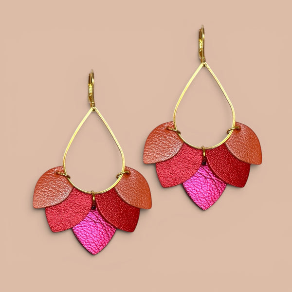 Boucles d'oreilles Nune modèle Aponi dorées à l'or fin avec pétales de cuirs corail nacré, coquelicot nacré et fushia métallisé, sur fond beige rosé