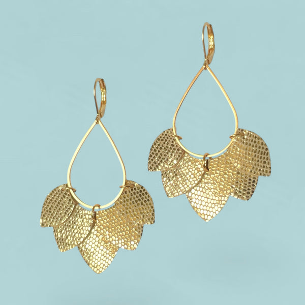 Boucles d'oreilles Nune modèle Aponi dorées à l'or fin avec pétales de cuir doré brillant façon serpent, sur fond vert