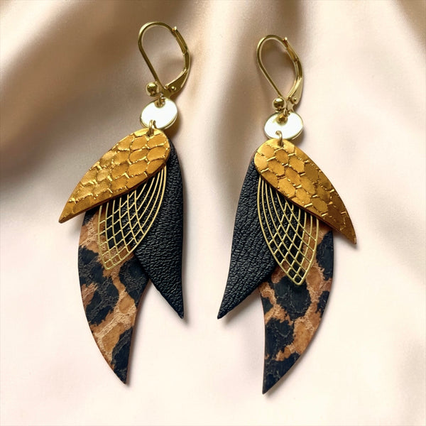 boucles d'oreilles dorées Nune modèle Ara en plumes de cuir bronze façon serpent, noir satiné et façon léopard, sur un  satin beige