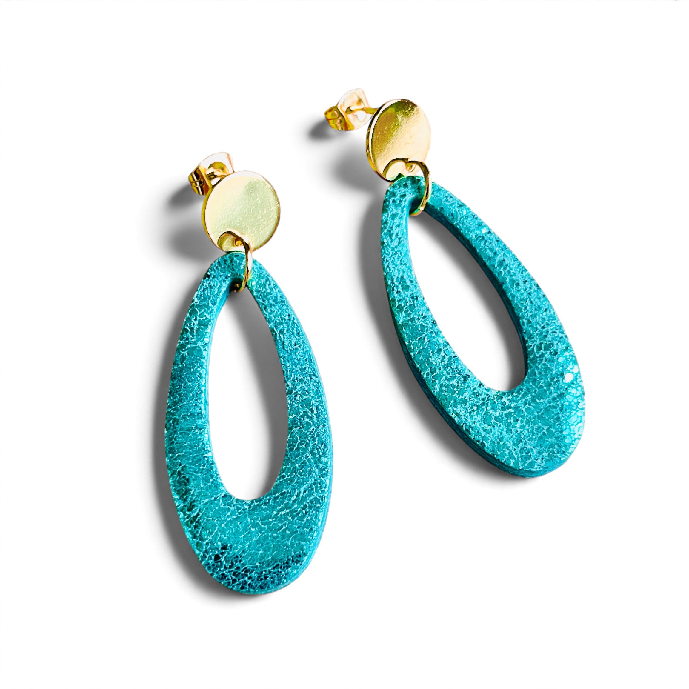Puces d'oreilles dorées Drys de la marque Nune, avec leurs anneaux ovales en cuir vert émeraude brillant, sur fond blanc