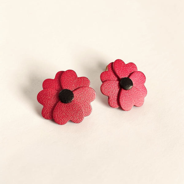 Boucles d'oreilles Nune en forme de petites fleurs , modèle Lalie, en cuirs coquelicot nacré & noir sur fond beige clair.