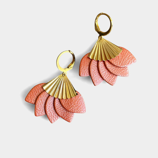 boucles d'oreilles dorées en forme éventail en cuir recyclé corail nacré de la marque Nune modèle Sakura, sur fond de cuir blanc