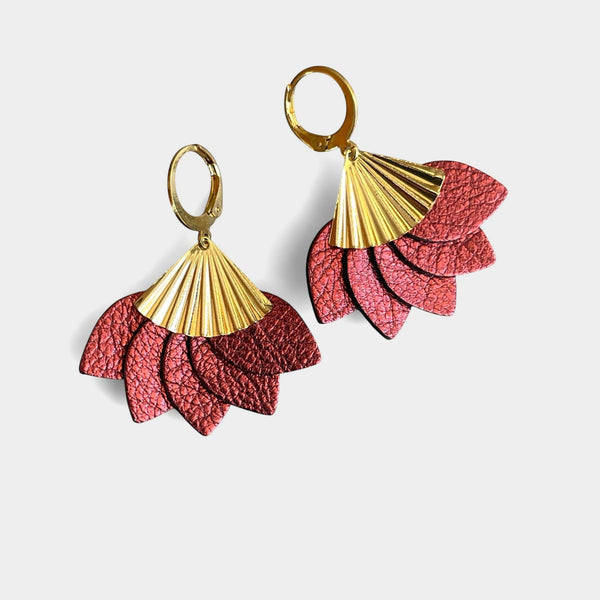 boucles d'oreilles dorées en forme éventail en cuir recyclé grenat métallisé de la marque Nune modèle Sakura, sur fond de cuir blanc