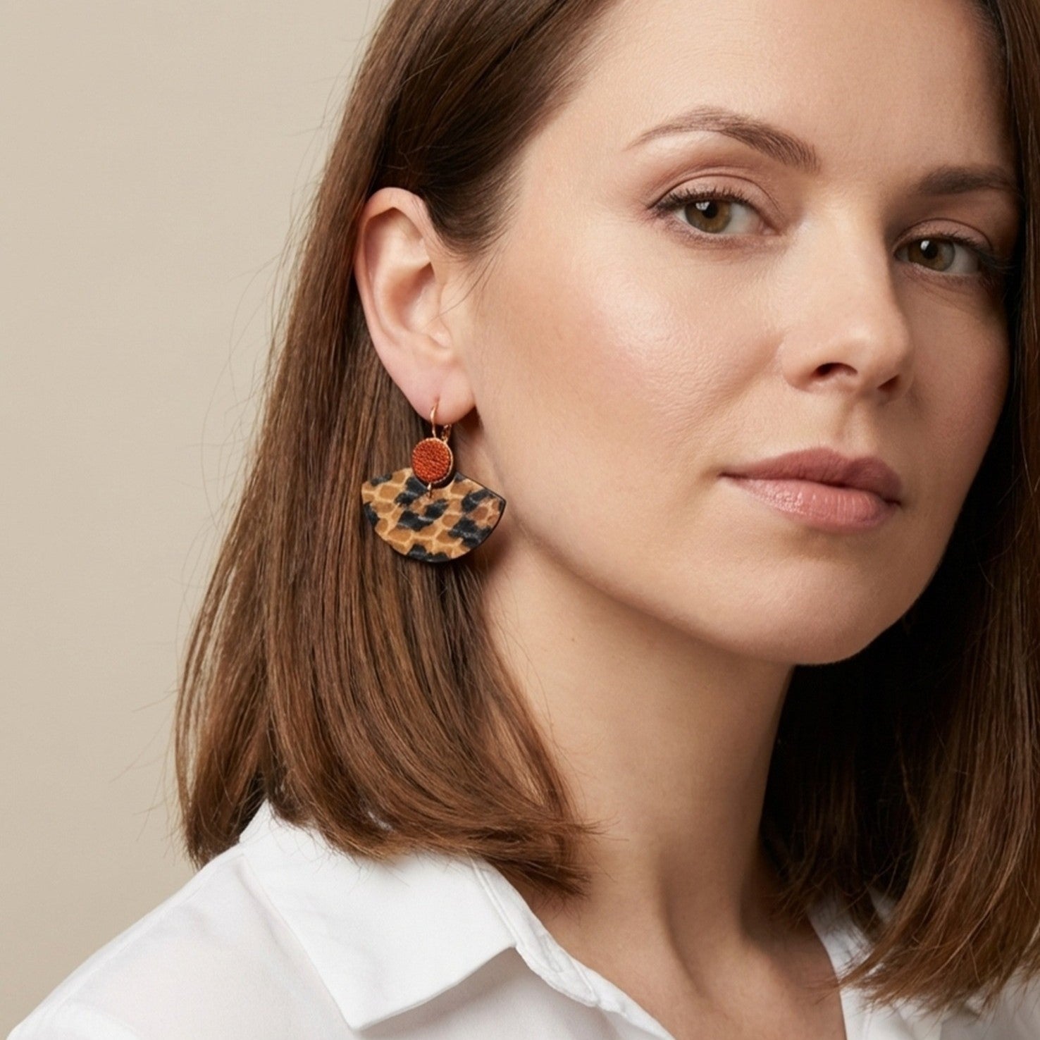 Boucles d'oreilles dorées pendantes, en forme d'éventails japonais en cuirs façon léopard et orange sanguine métallisé , portées aux oreilles par une femme brune