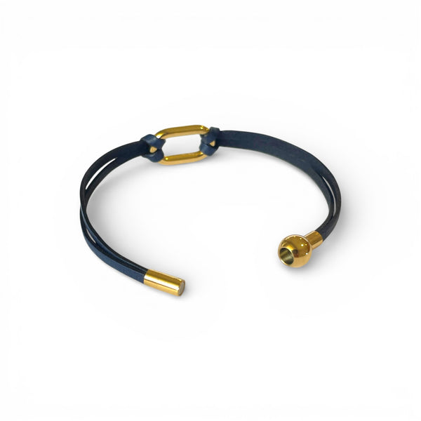Bracelet à boucle dorée en fins liens de cuir bleu marine, avec fermoir aimanté doré, présenté ouvert, sur fond blanc