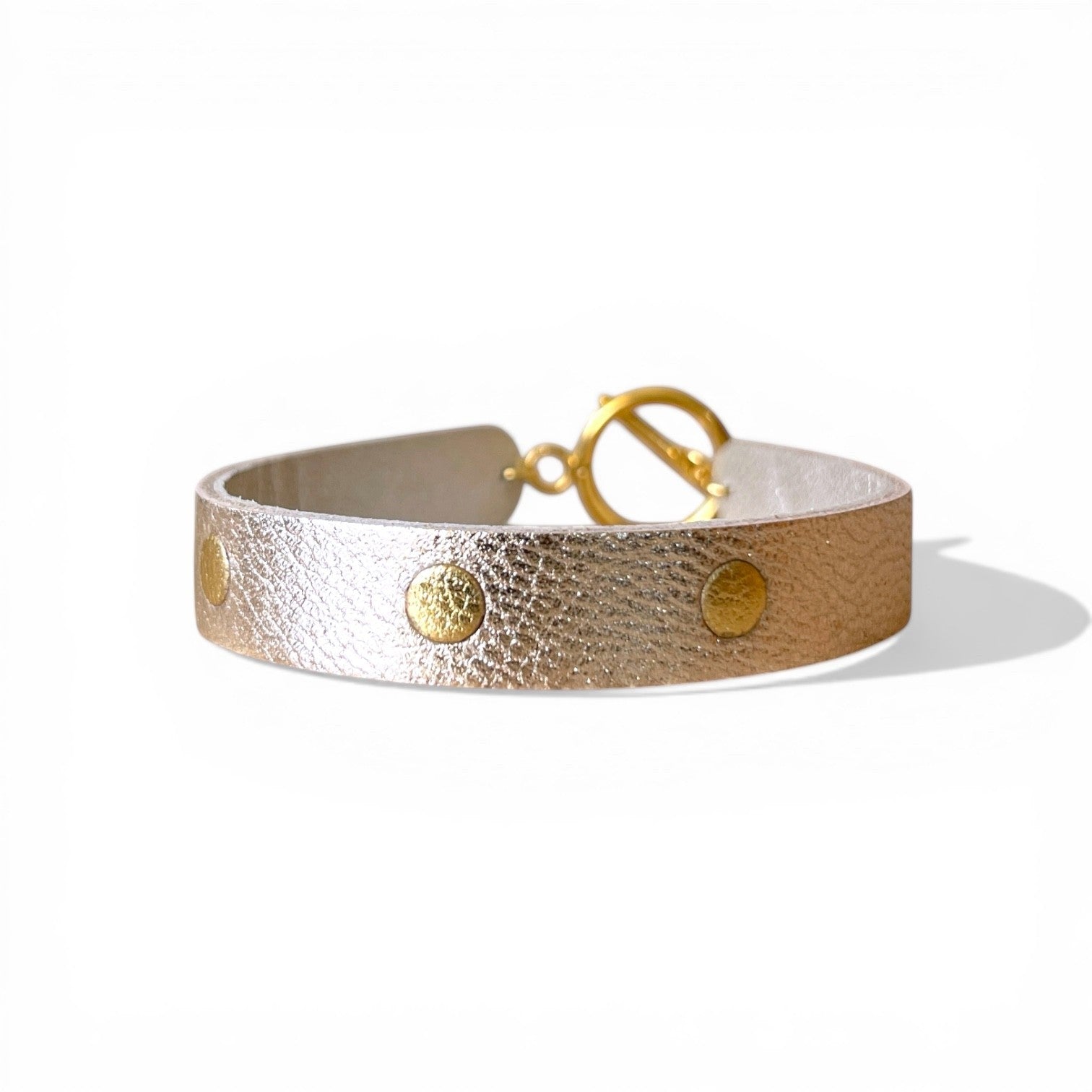 Bracelet doré en cuirs bicolore argent et or, sur fond blanc