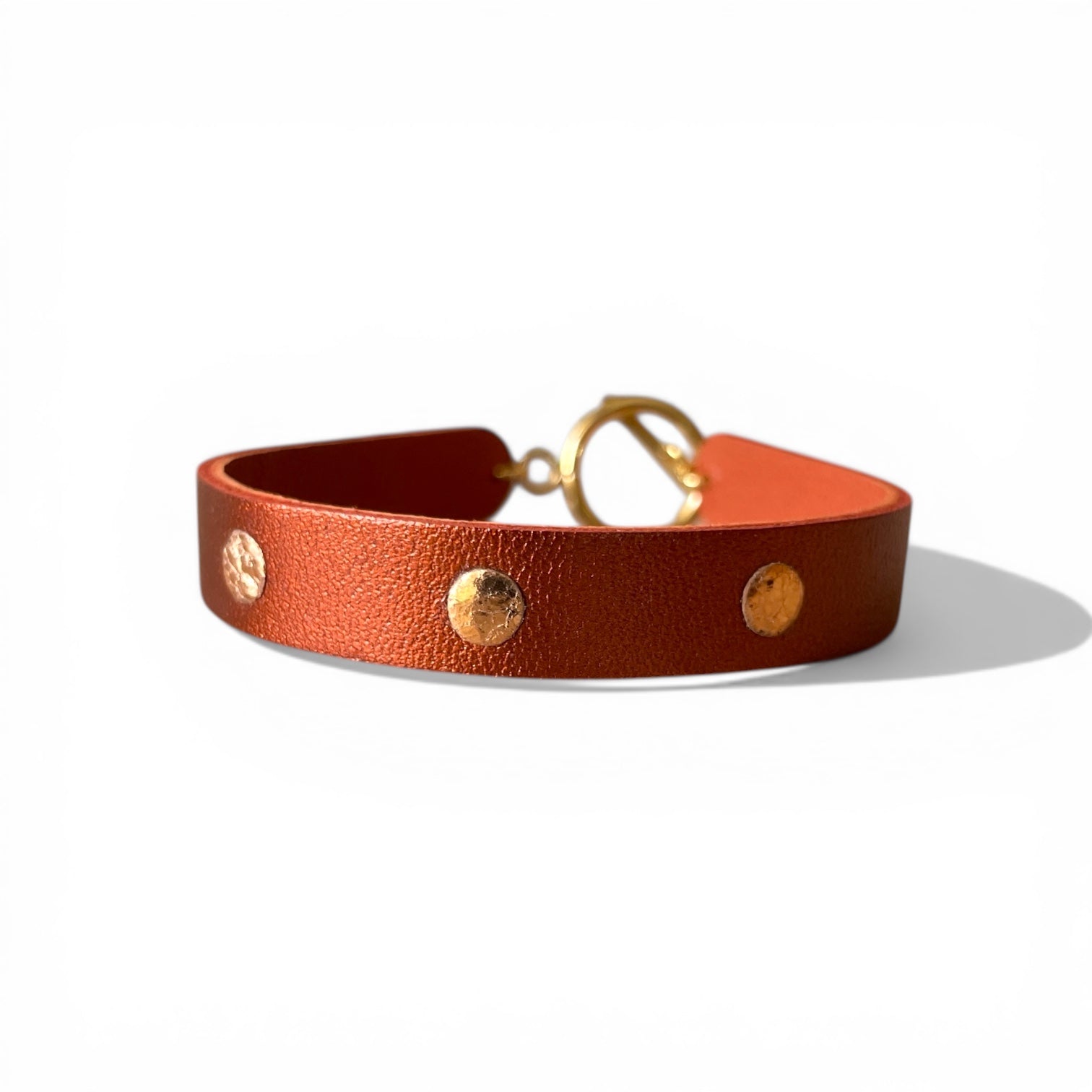 Bracelet doré en cuirs bicolore terracotta métallisé et or rosé froissé, sur fond blanc