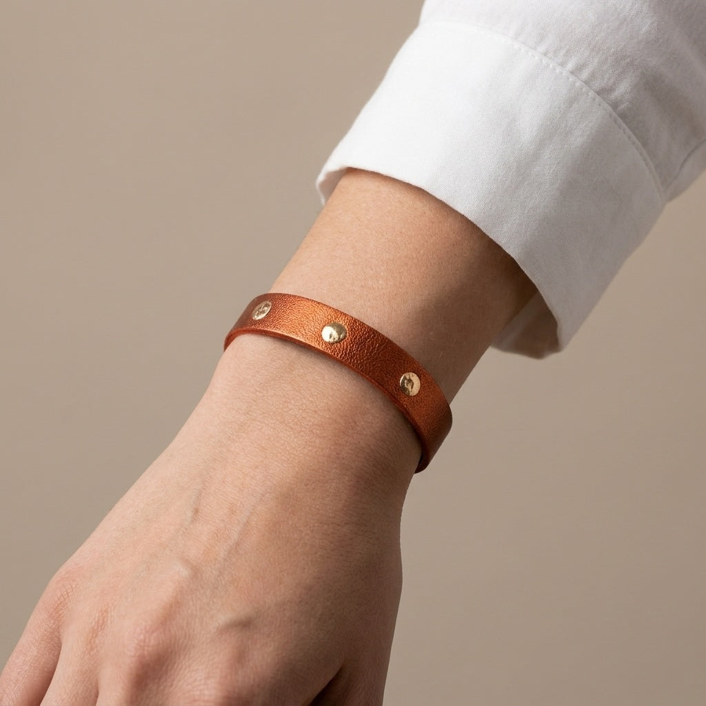 Bracelet doré en cuirs bicolore terracotta métallisé et or rosé froissé, porté au poignet