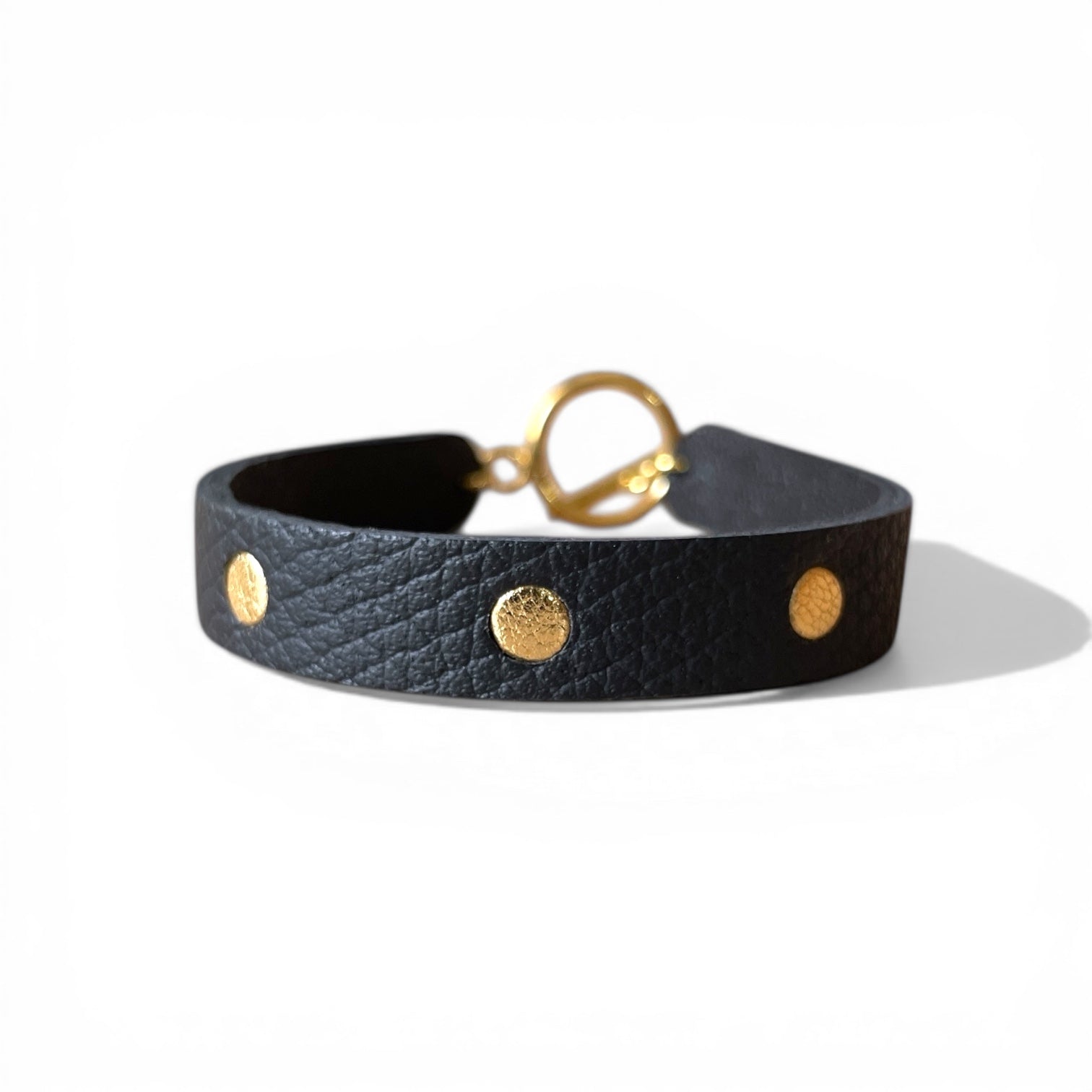 Bracelet doré en cuirs bicolore noir grainé et or, sur fond blanc