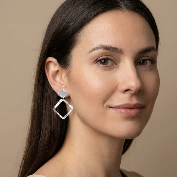 Boucles d'oreilles puces argentées en métal martelé avec pendentif en forme de losange, portées aux oreilles