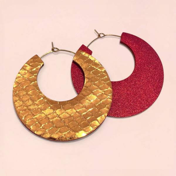 NUNE grandes boucles d'oreilles créoles dorées rondes tout-cuir Circus, un côté rubis métallisé, l'autre côté bronze brillant façon serpent, à plat sur fond beige rosé