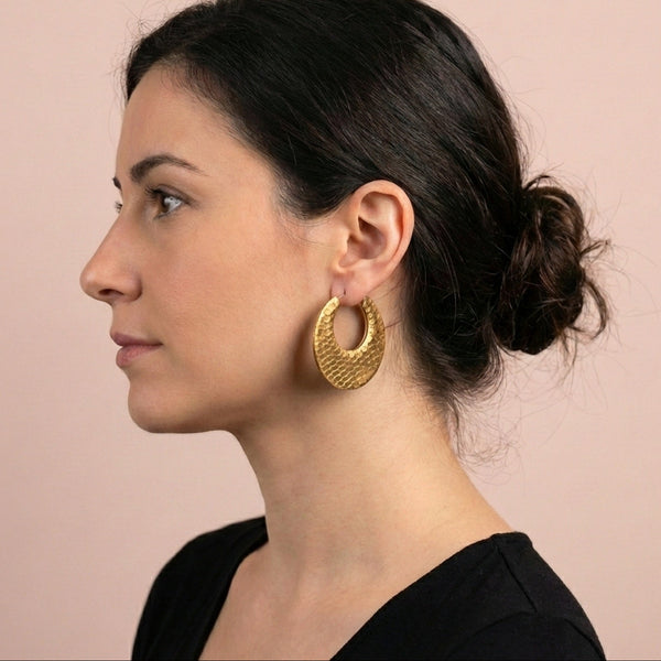 Jeune femme à chignon vue de profil portant les grandes boucles d'oreilles créoles rondes tout-cuir Circus, vues du côté bronze façon serpent