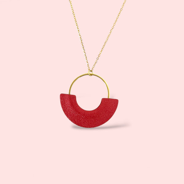 Collier fin  modèle Mezzaluna doré avec pendentif rond en forme de demi-lune en cuir recyclé coquelicot nacré, vue de biais, sur fond rose pastel